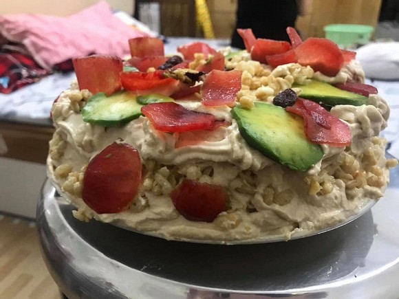 A decorated birthday cake with an excess of fruit slices, leaving everyone wondering: How should we cut the cake now?