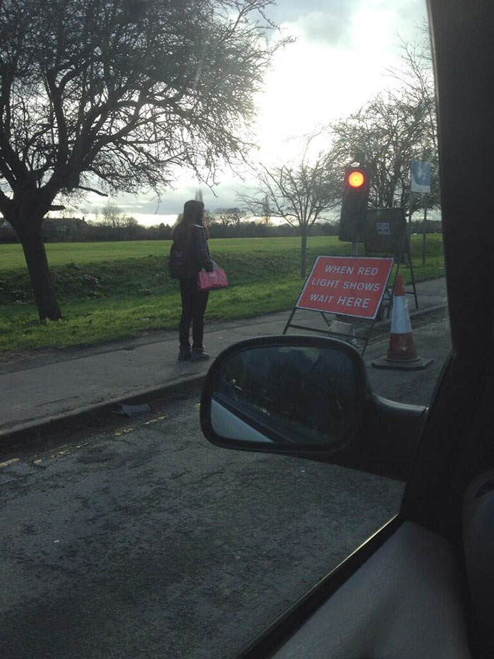 The warning sign says, 'When the light is red, wait.' That girl has been waiting for a long time...