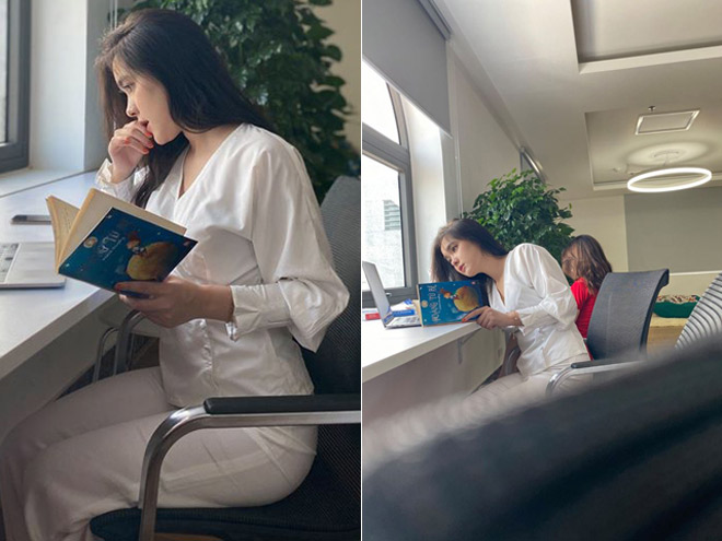 Candid shot of Thien Trang in a pure white outfit, with loose hair, light makeup, and focused on the pages of her book.
