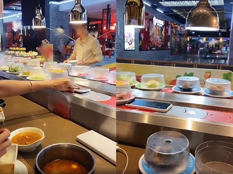 The guy comfortably places his phone on the conveyor hotpot
