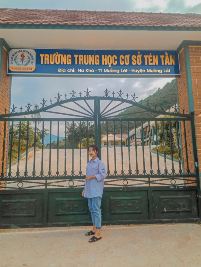 Lương Thị An taking a photo at the school gate.