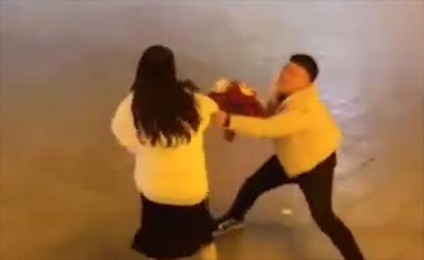 The girl struggles against the young man's attempts to hold her back
