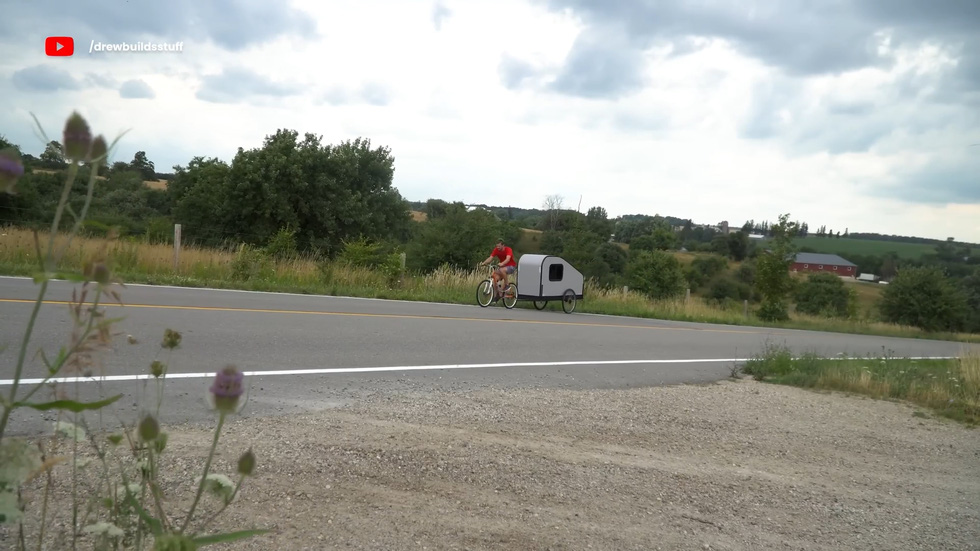 Riding a bike uphill while towing a 'house' is not easy at all - Photo: Drew Builds Stuff/YouTube